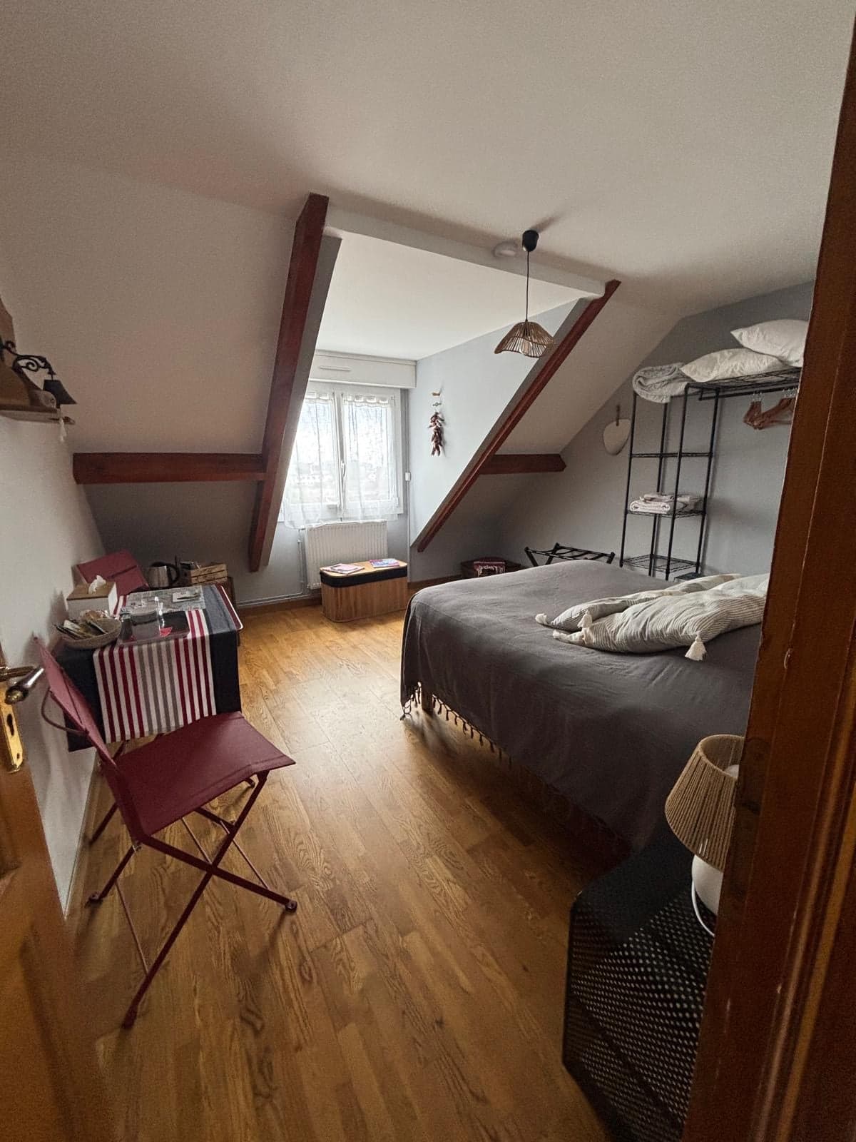 La chambre vue de la porte : poutres rouges et fenêtre sur le jardin